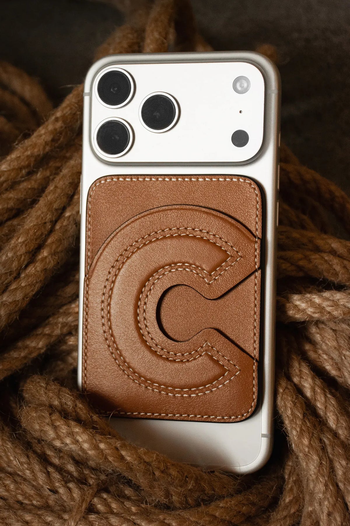 Initial MagSafe cardholder in Canyon leather with the letter C, on a phone resting on rope